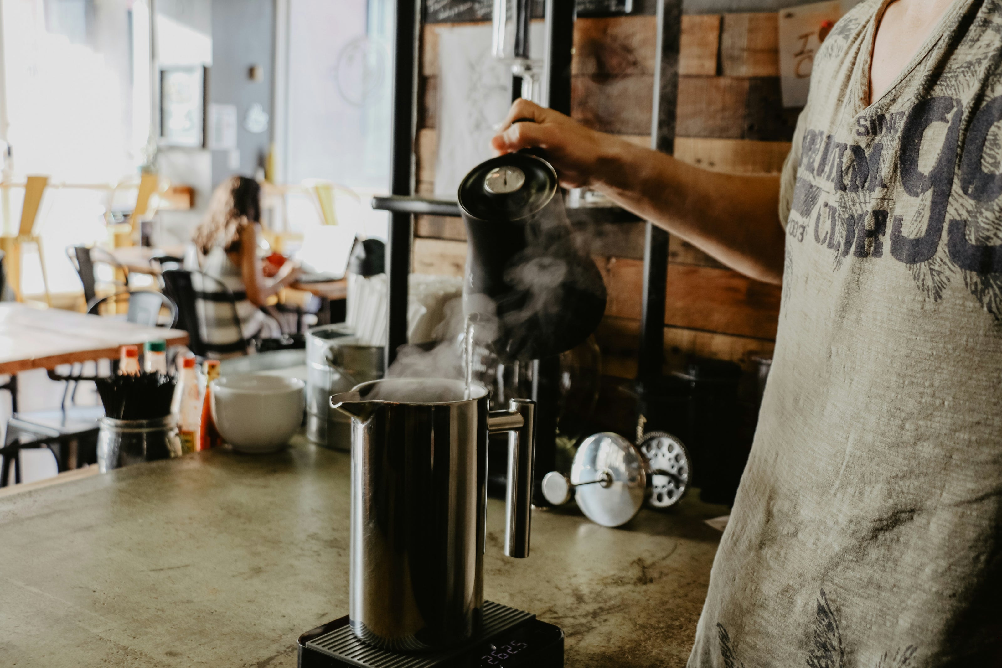 Barista schenkt heißes Wasser in French Press. René Porter