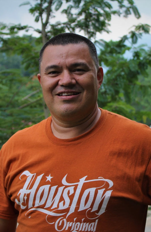 Mann mit orangenem T-shirt vor grünem Hintergrund
