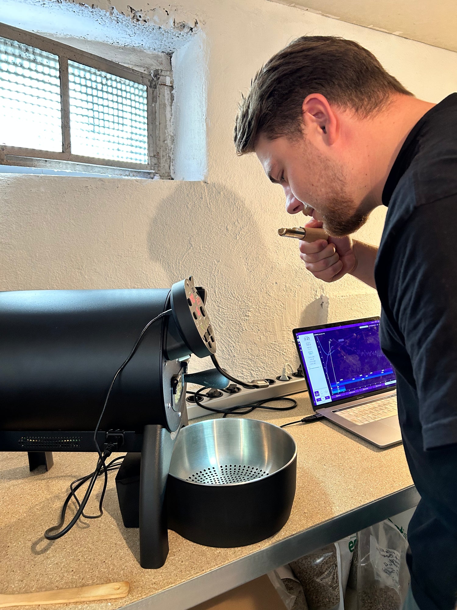 Junge riecht an Kaffee und steht vor kleinem Röster.