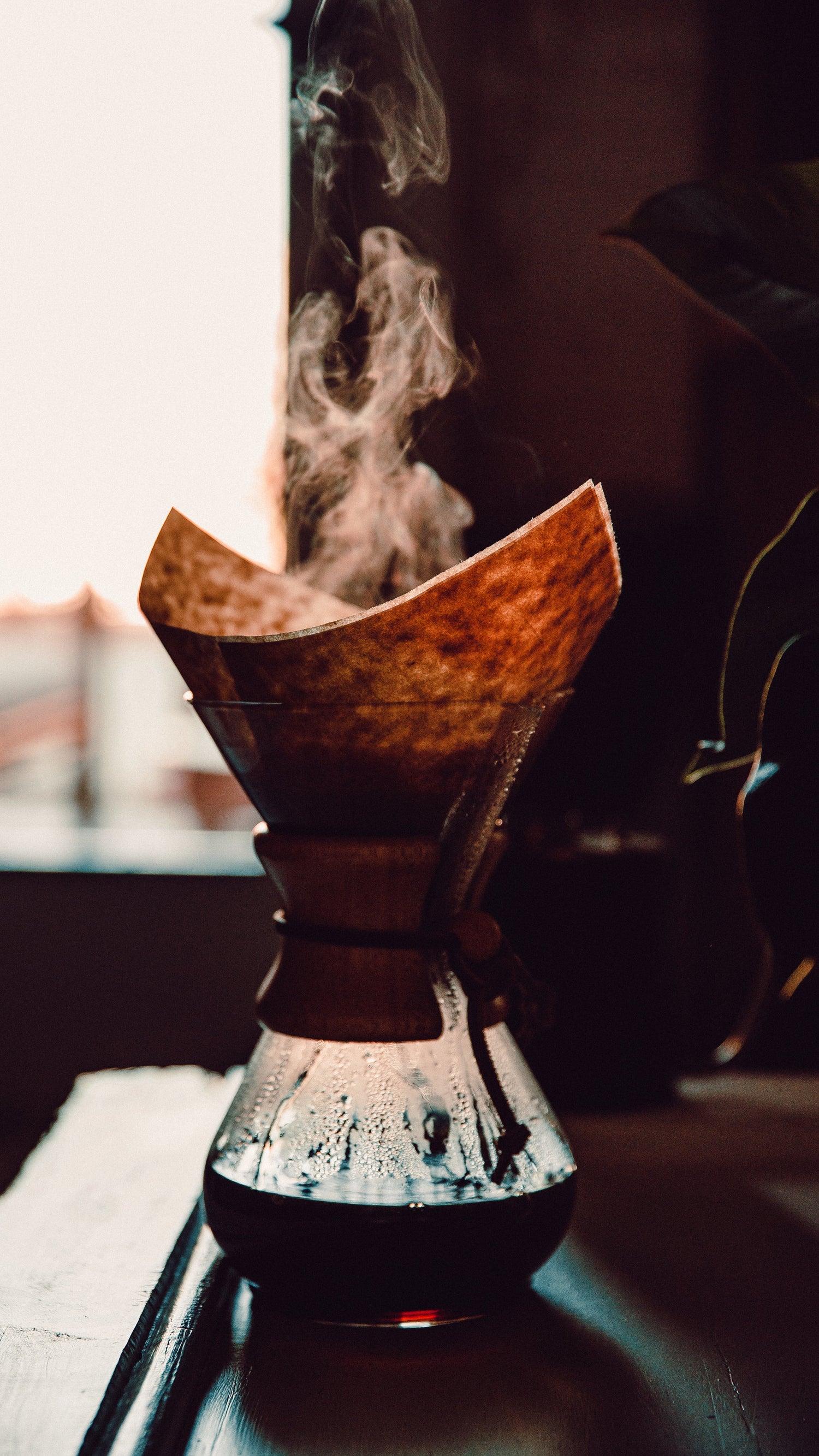 Große Filterkanne mit braunem Filterpapier. Heißer Kaffee dampft, mystische Stimmung.