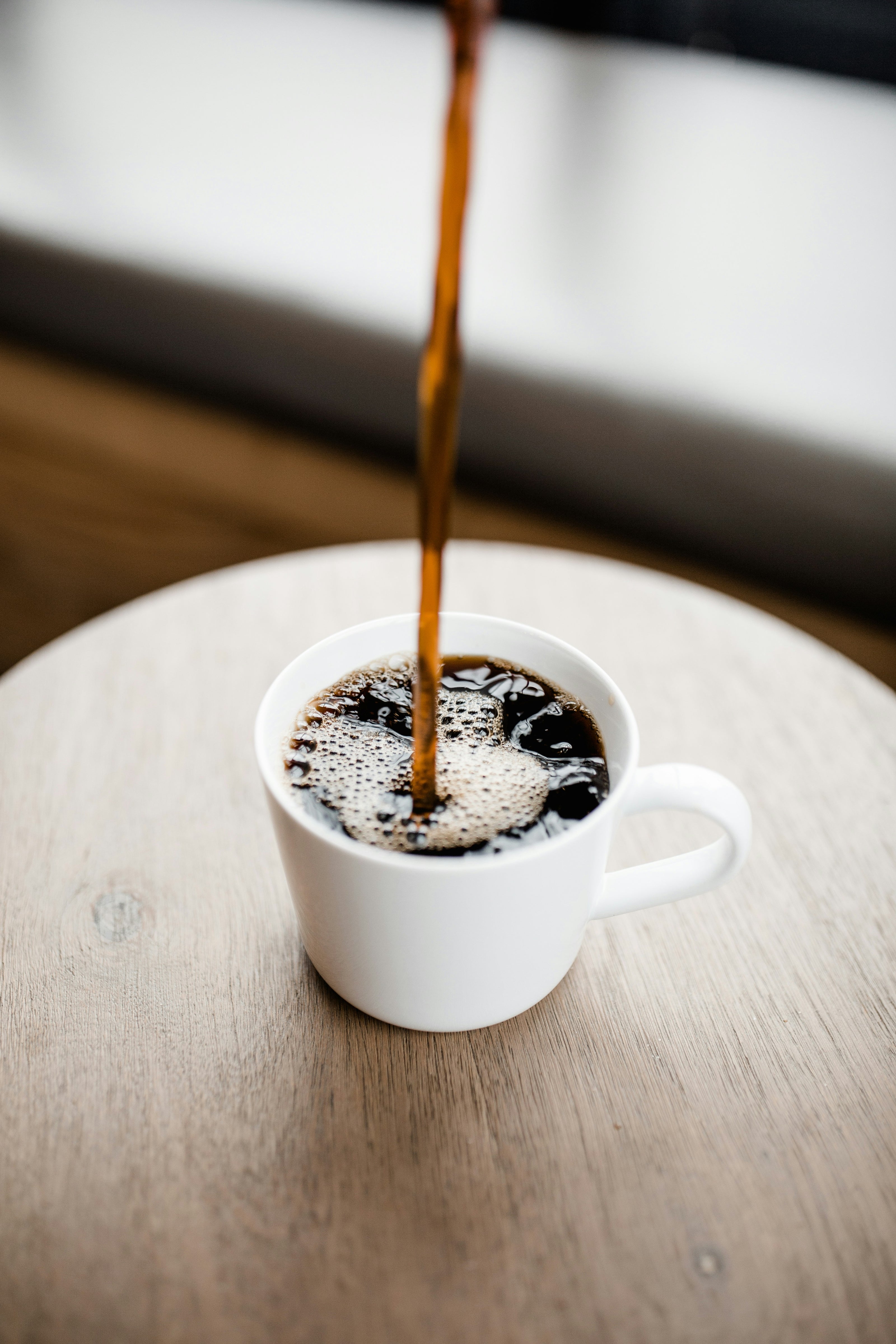 URHEBER: Andrew Neel. Weiße Tasse, Kaffee wird eingegossen.