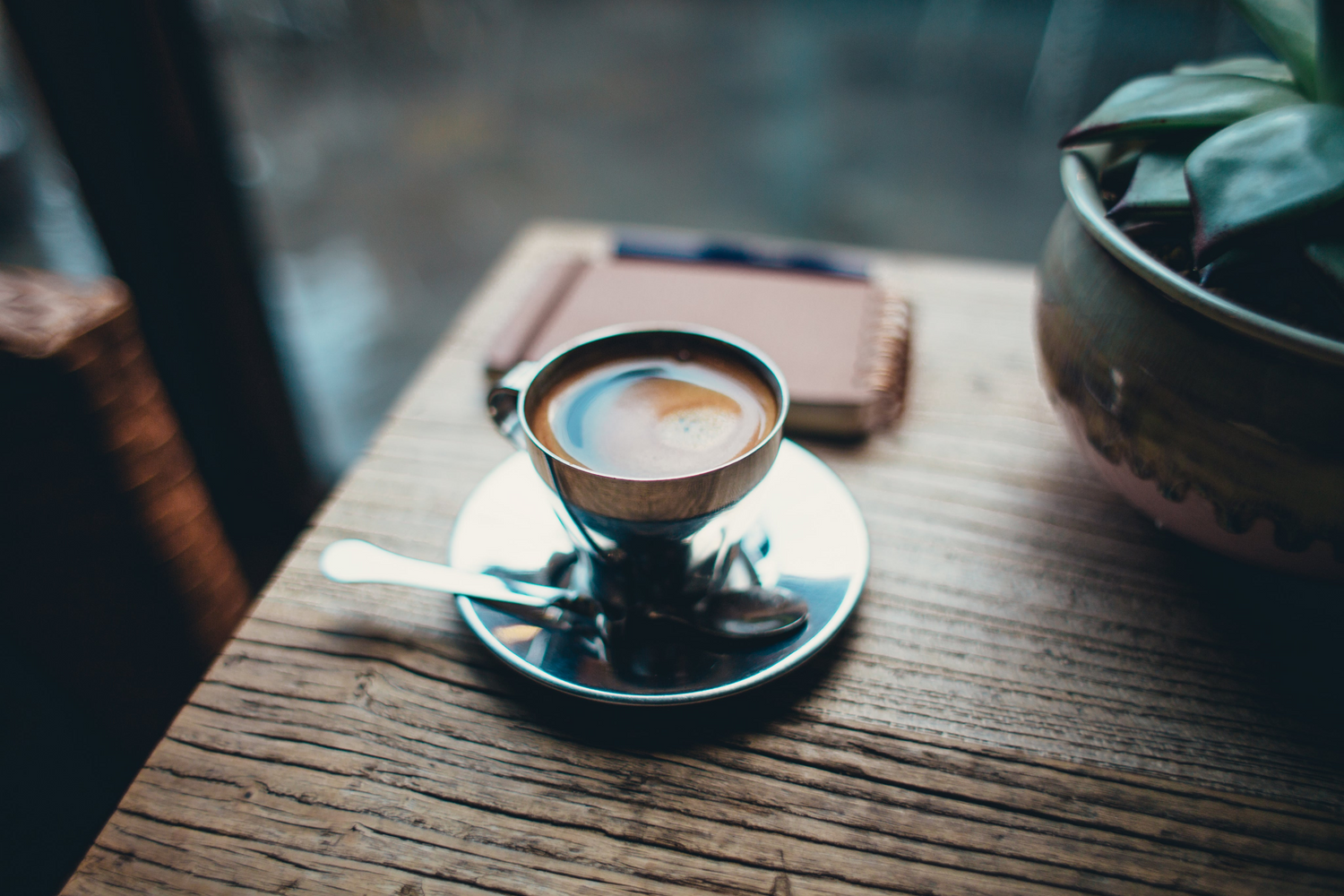 Espresso in silberner Tasse auf Holztisch