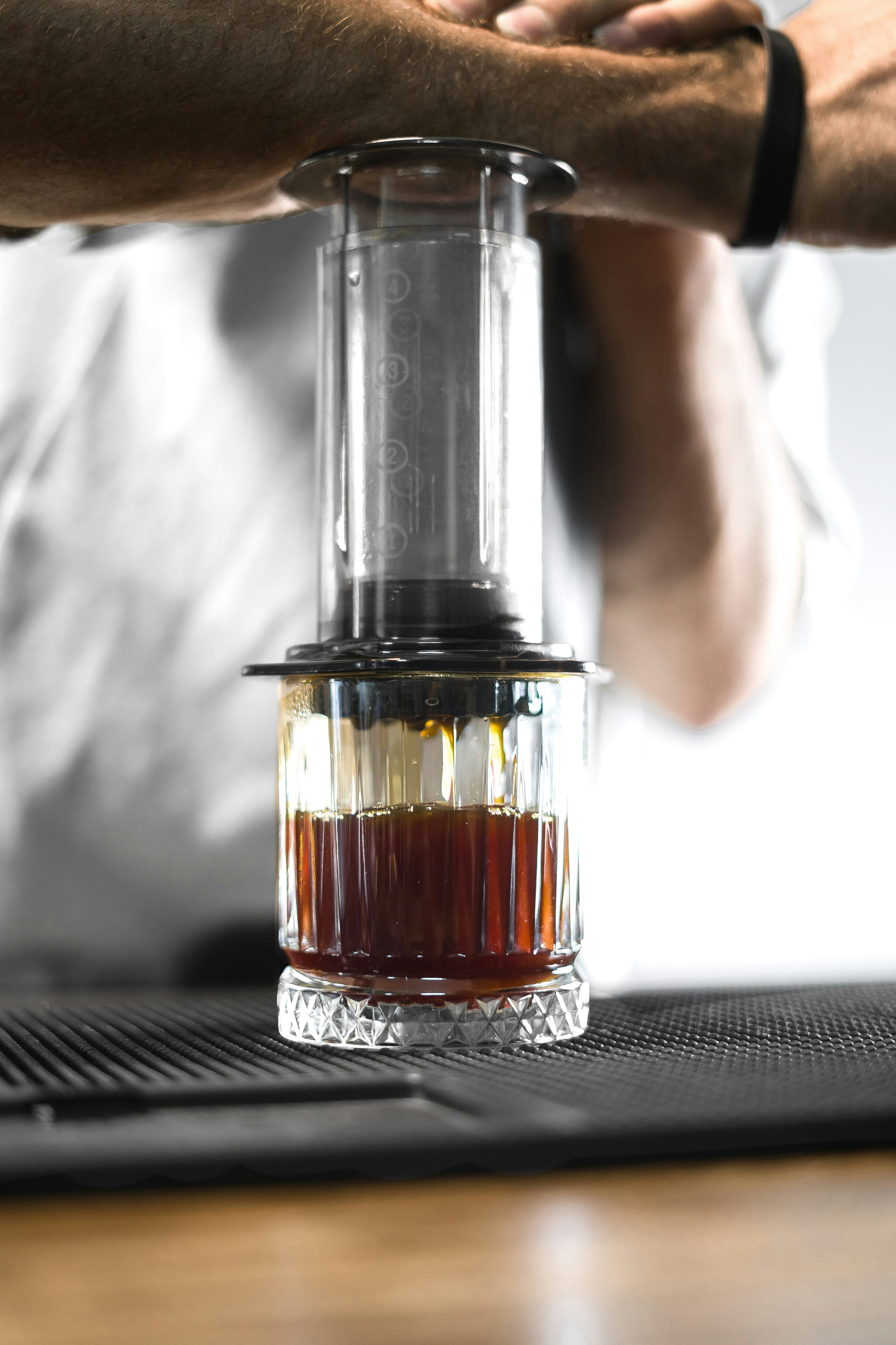 URHEBER: Pouya Hajibagheri. Durchsichtige Aeropress mit Glas darunter, Kaffee wird extrahiert.